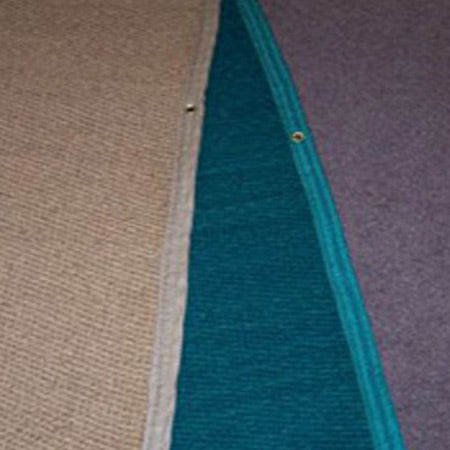 Close-up of three different textured fabric mats in beige, teal, and purple, with teal edging and metal grommets