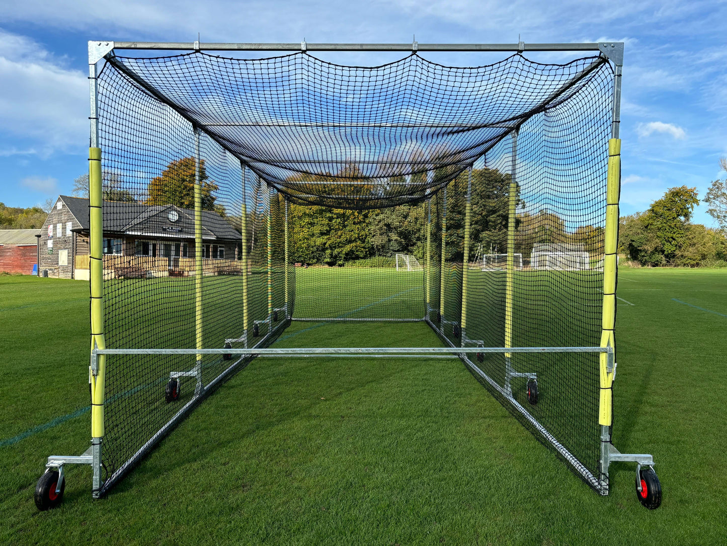 11m Anti-Vermin Mobile Batting Cage on a grass field with clear sky and background buildings.