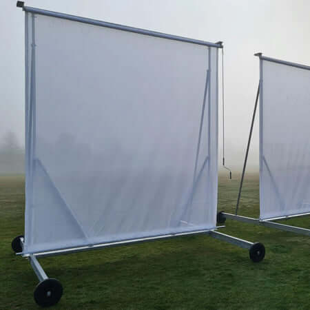4M X 4M Roller Mesh Sight Screen set up on a field with fog in the background, showcasing its sturdy design.