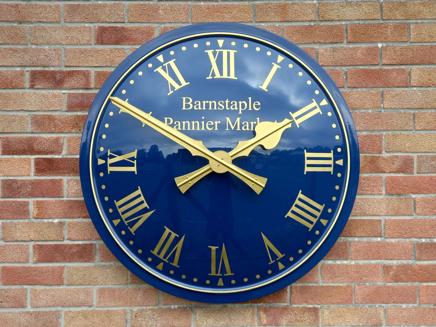 Cricket Pavilion Clocks on a wall with a blue dial and gold hands, showcasing a traditional design.