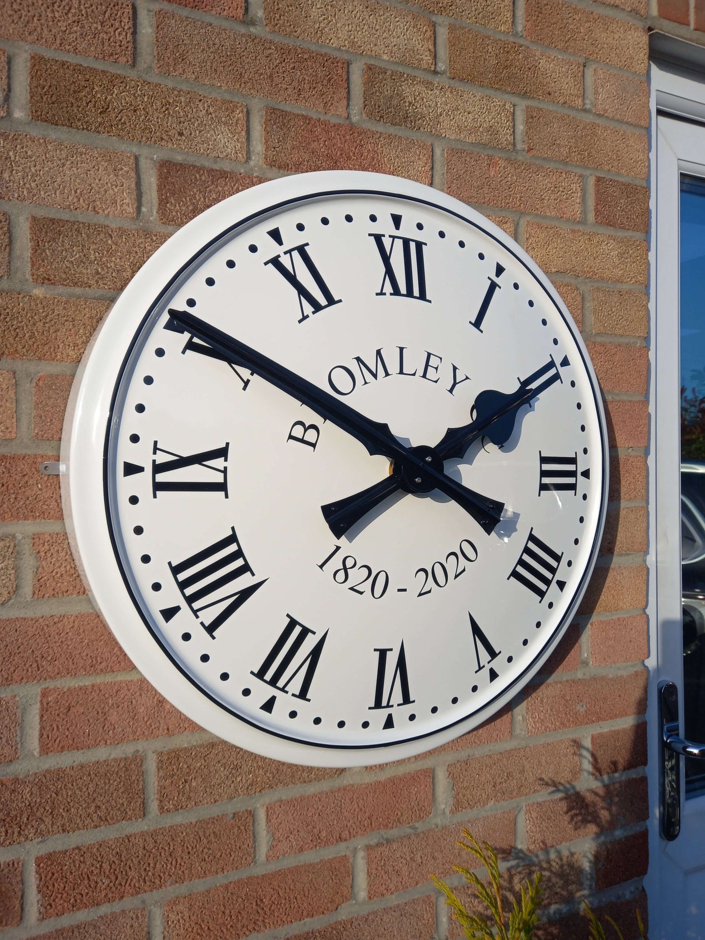 Cricket Pavilion Clocks displayed on a brick wall with traditional Roman numerals and elegant finish.