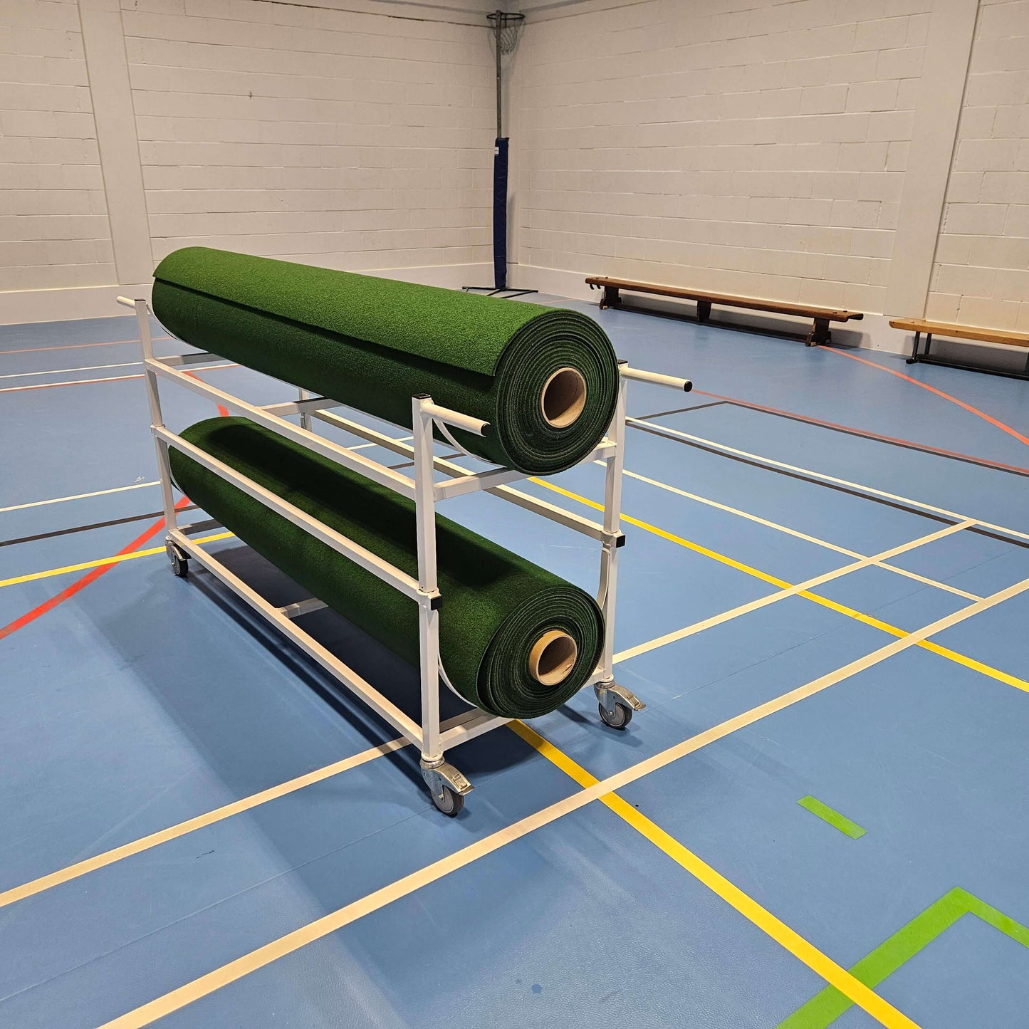 Piggy Back Carpet Trolley holding two green mats on a gym floor with colorful markings.