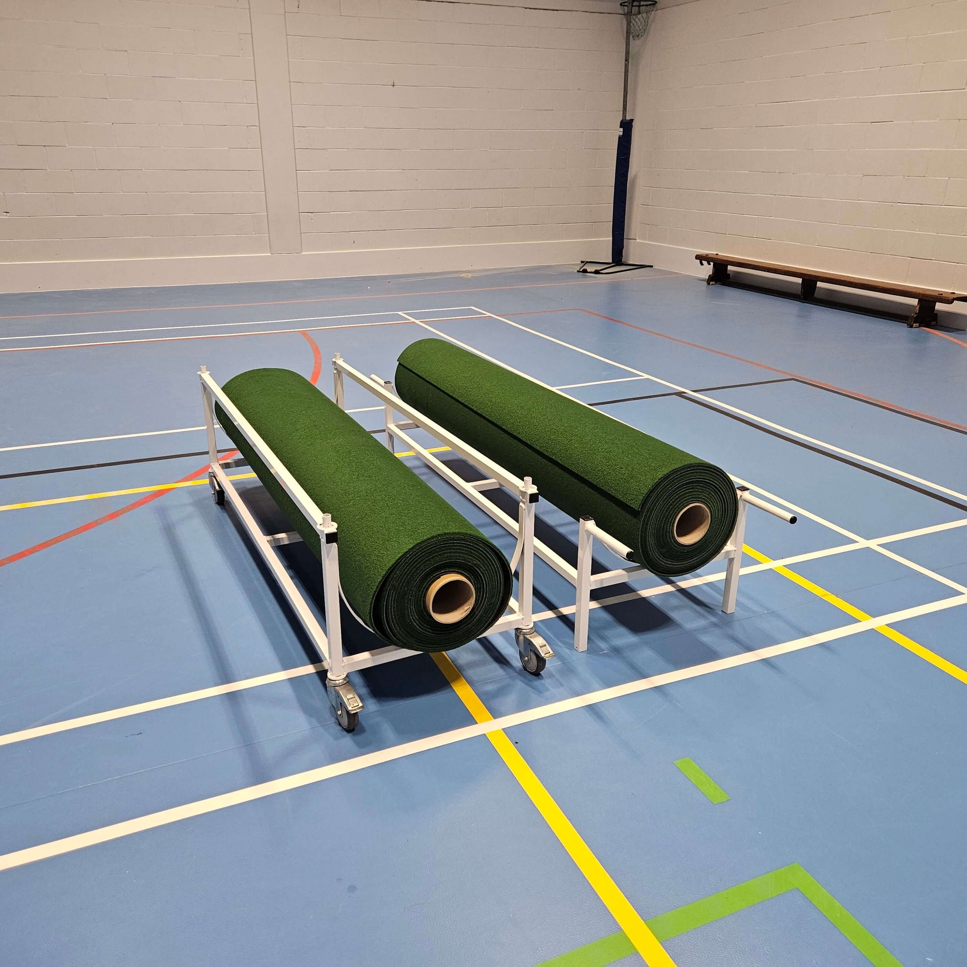 Piggy Back Carpet Trolley with two rolls of green carpet on a gymnasium floor.